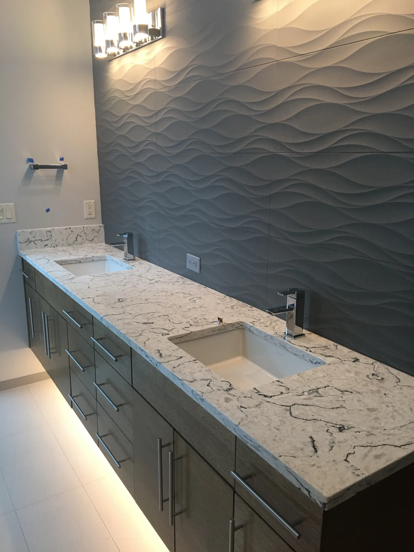 White granite double vanity with textured wave accent wall