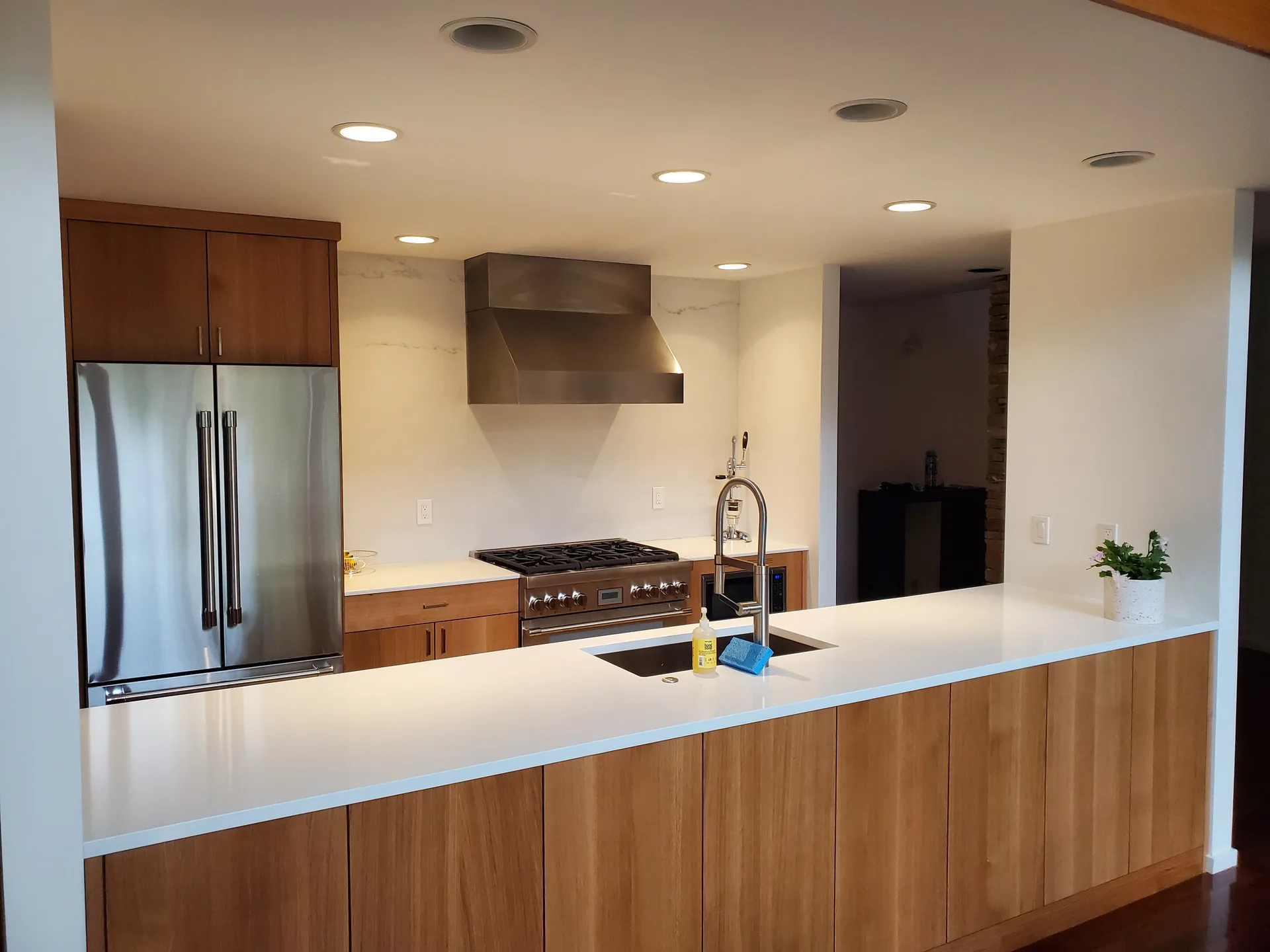 White quartz waterfall peninsula with wood cabinets