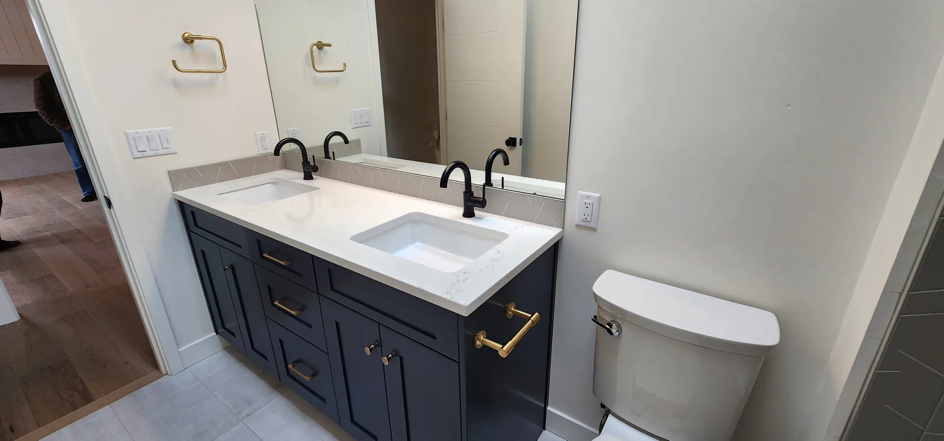 White quartz countertop on navy vanity with brass and black fixtures