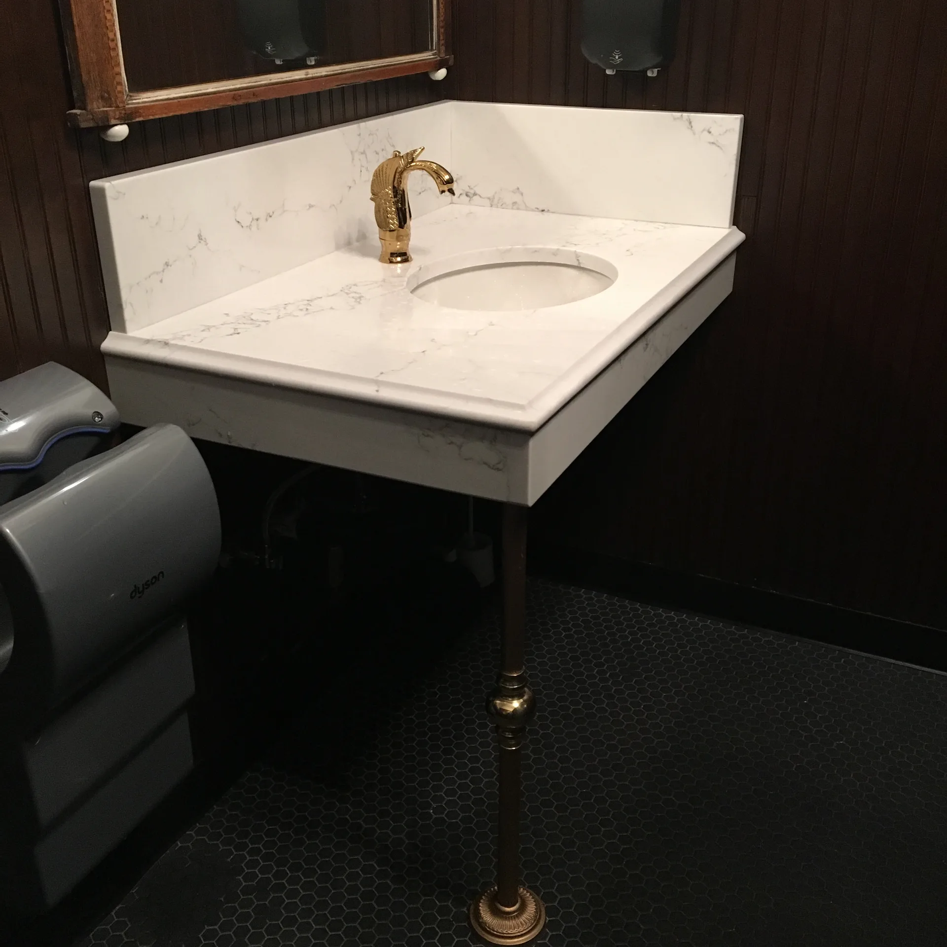 White Carrara-style marble console sink with brass legs