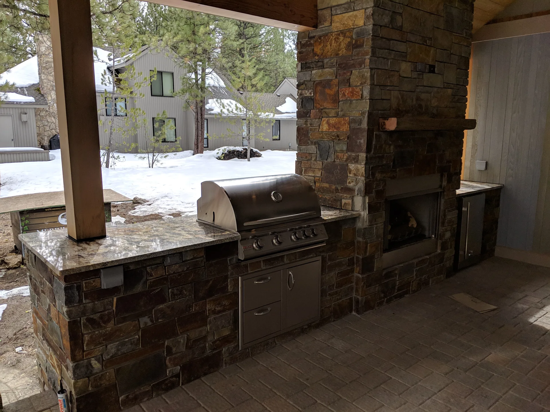 Outdoor kitchen with granite BBQ island and stacked stone fireplace