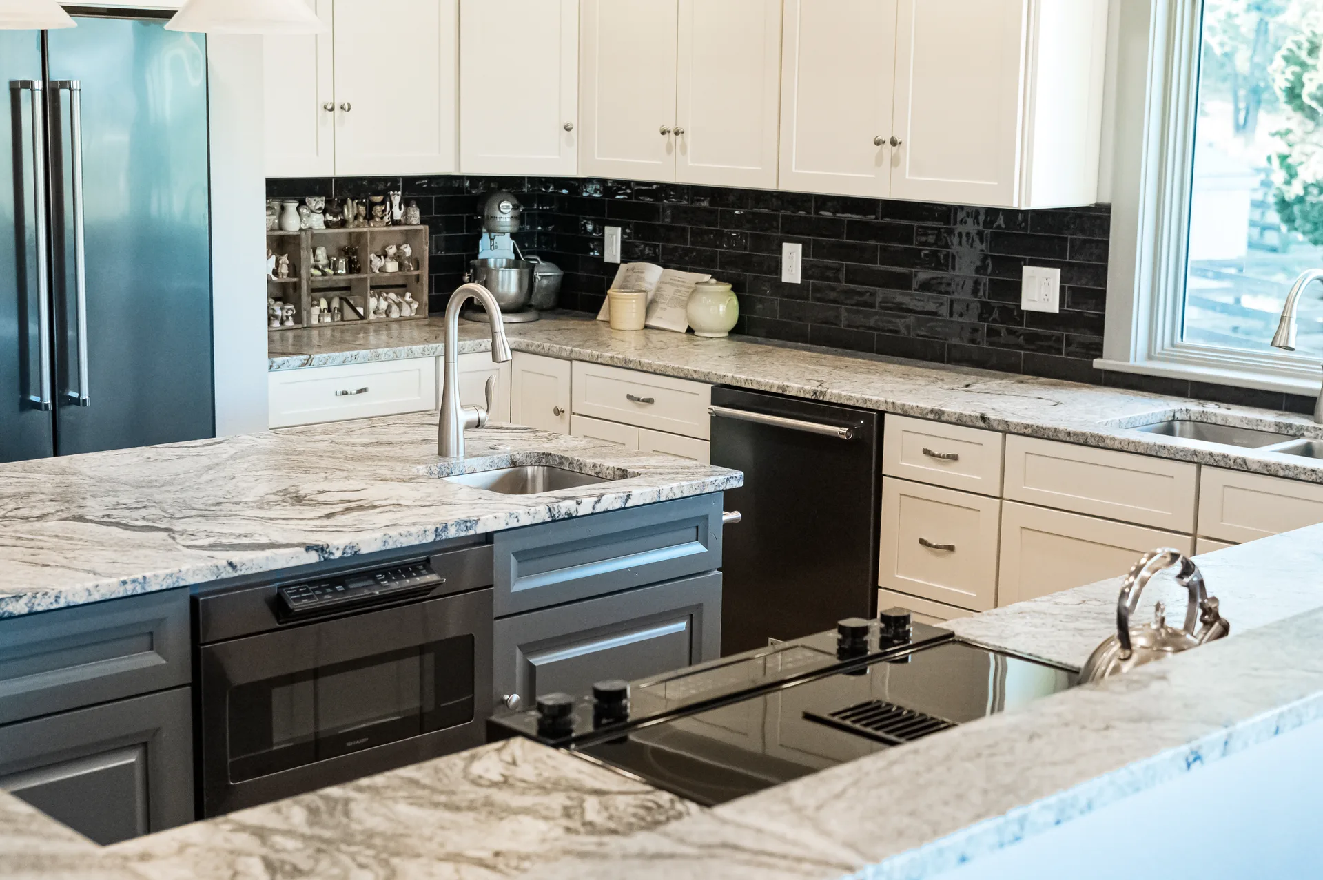 White and gray granite kitchen countertops with dark glass backsplash