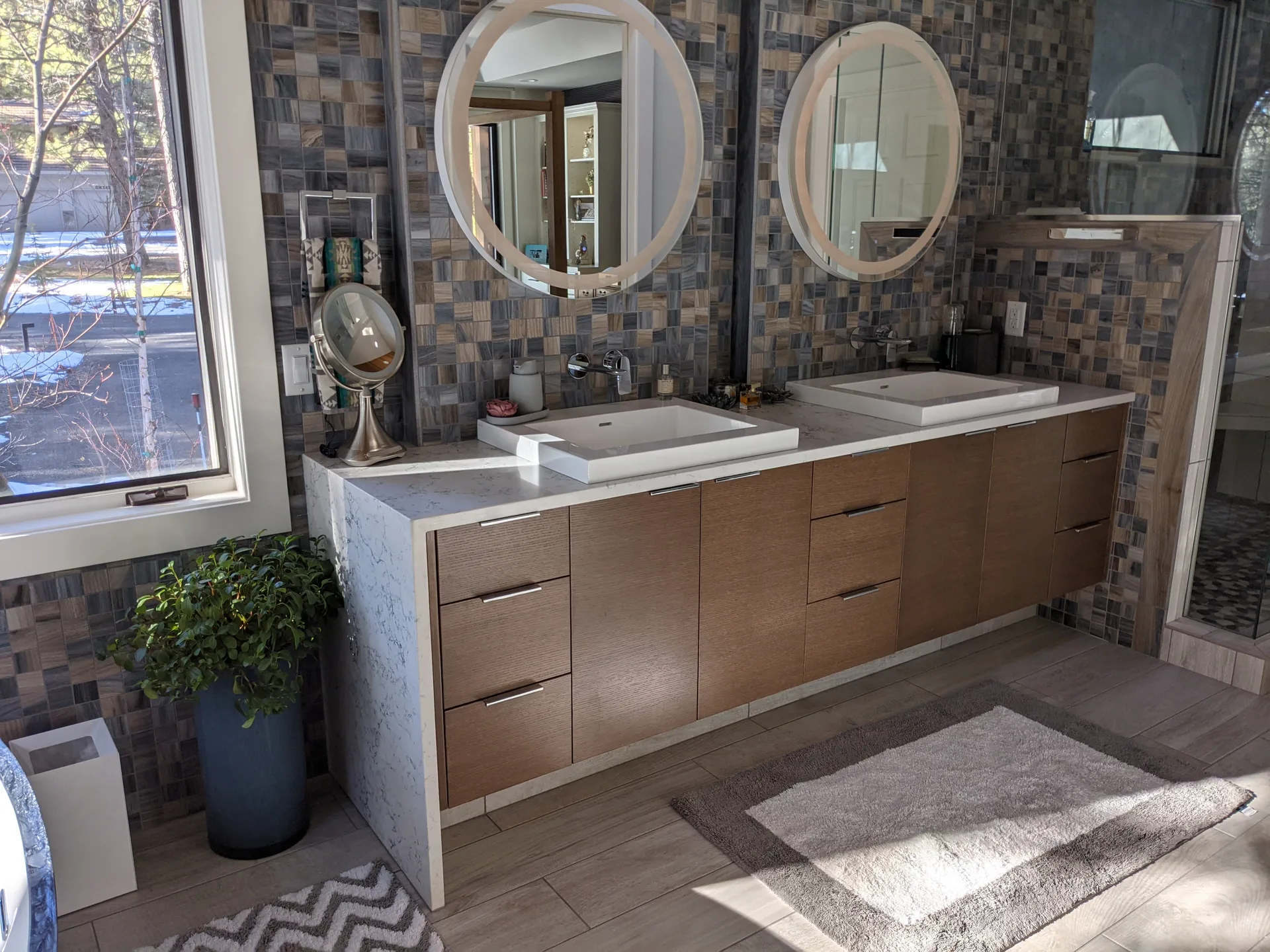 Floating wood double vanity with white marble top and mosaic tile backsplash