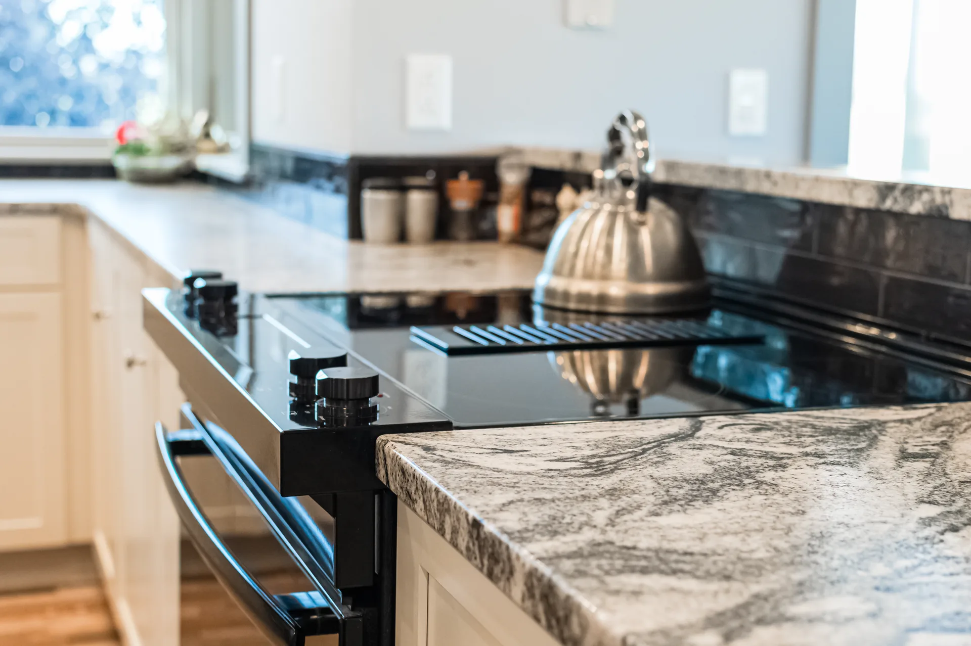 Veined white and gray granite countertop with downdraft cooktop