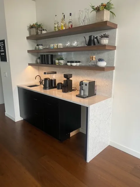 Quartz beverage bar countertop with floating wood shelves and black cabinets